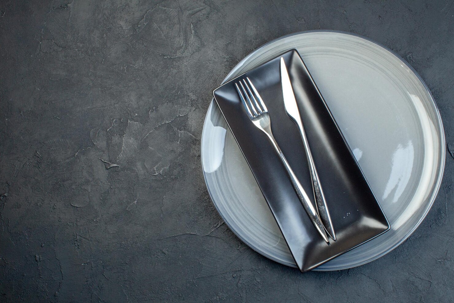 vista superior plato largo negro tenedor cuchillo plato gris sobre fondo oscuro cubiertos vidrio colorido feminidad comida cocina horizontal 140725 156861